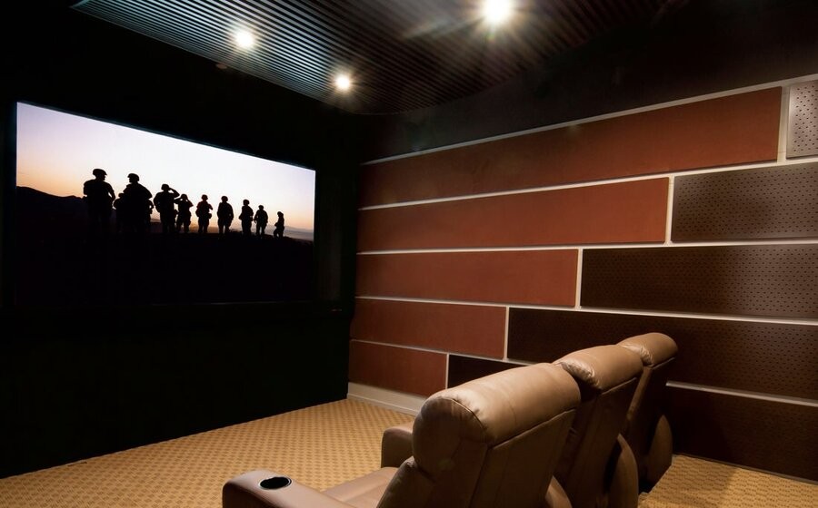  A home theater featuring a large screen, in-wall speakers, and comfy seating.
