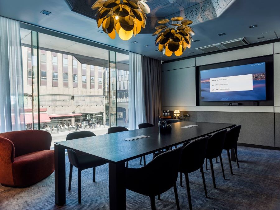 A Zoom Room hotel conference room with a display, table, and chairs.