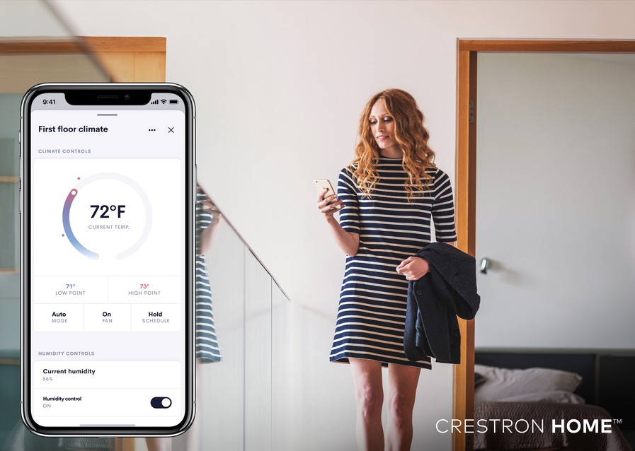 Woman looking at her phone in the background. In the foreground is the Crestron app on the phone displaying 72 degrees inside. 