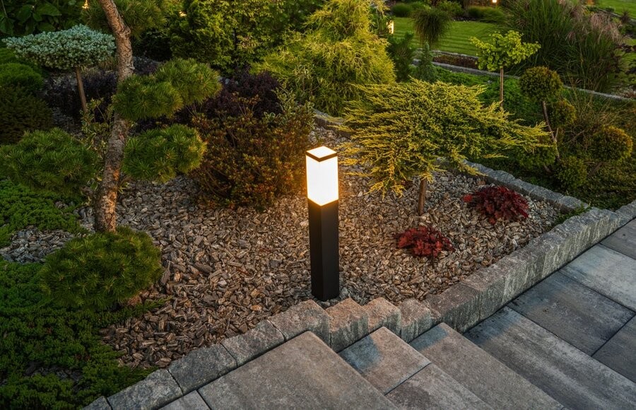 An illuminated landscape lighting fixture next to an outdoor staircase.