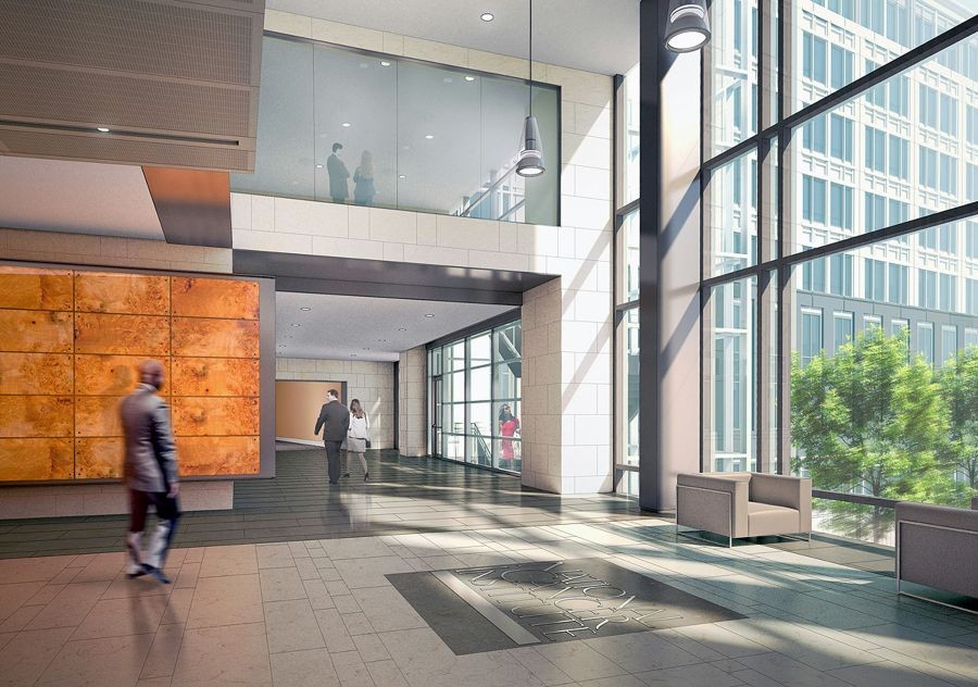 Spacious, sunlit modern office lobby with large glass windows, sleek seating, and people walking through the open corridor.